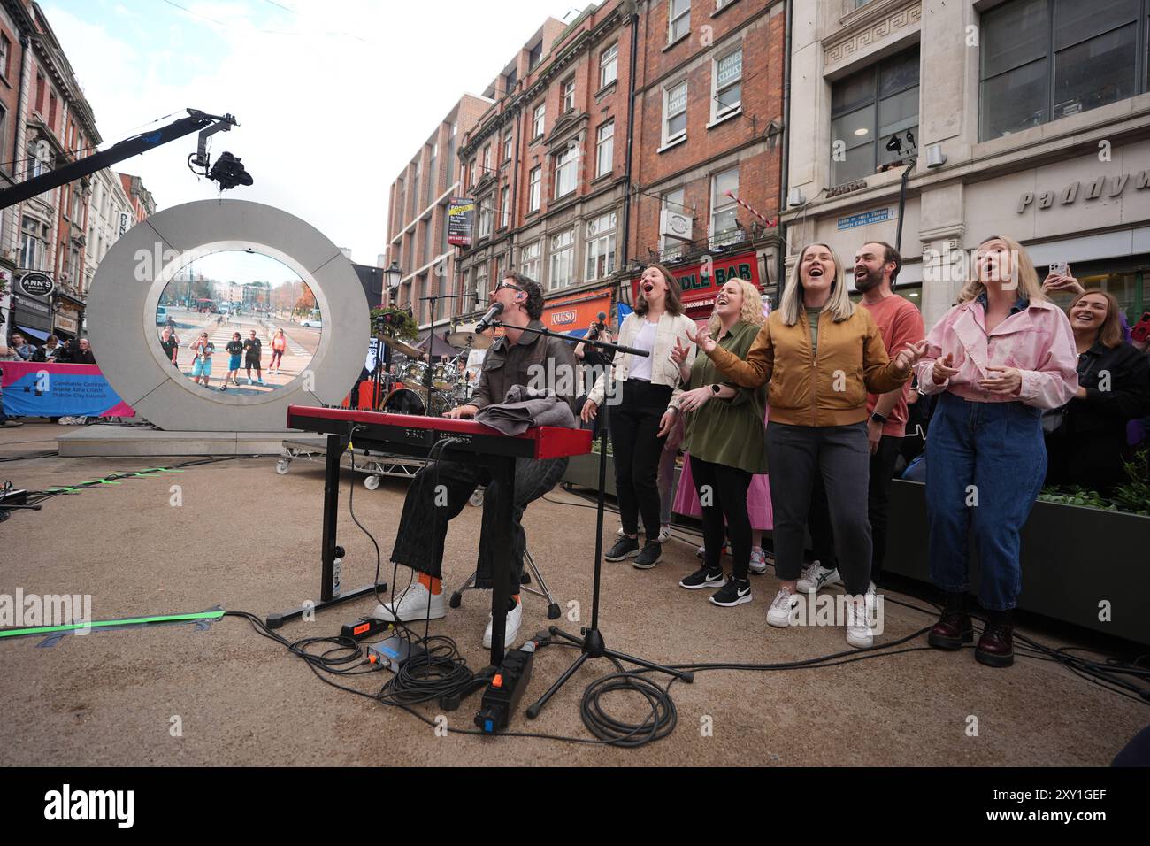 Cian Ducrot und Flash Mob Choir treten auf dem Dublin-Portal auf und streamen live nach New York, Vilnius und Lublin. Bilddatum: Dienstag, 27. August 2024. Stockfoto