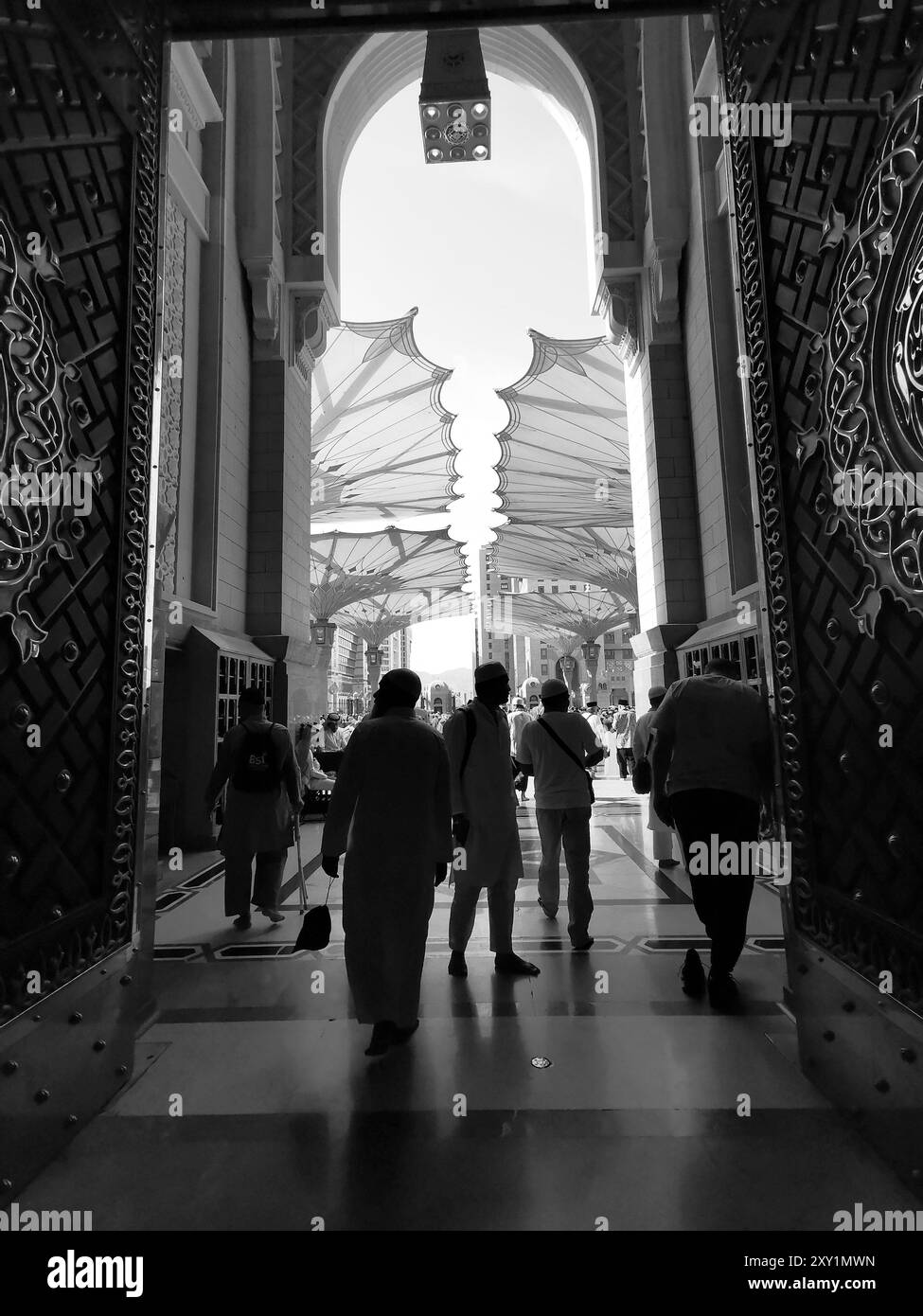 Schwarz-weißes Bild der Silhouette muslimischer Pilger am Eingang der Nabawi-Moschee in Medina, Königreich Saudi-Arabien. Stockfoto