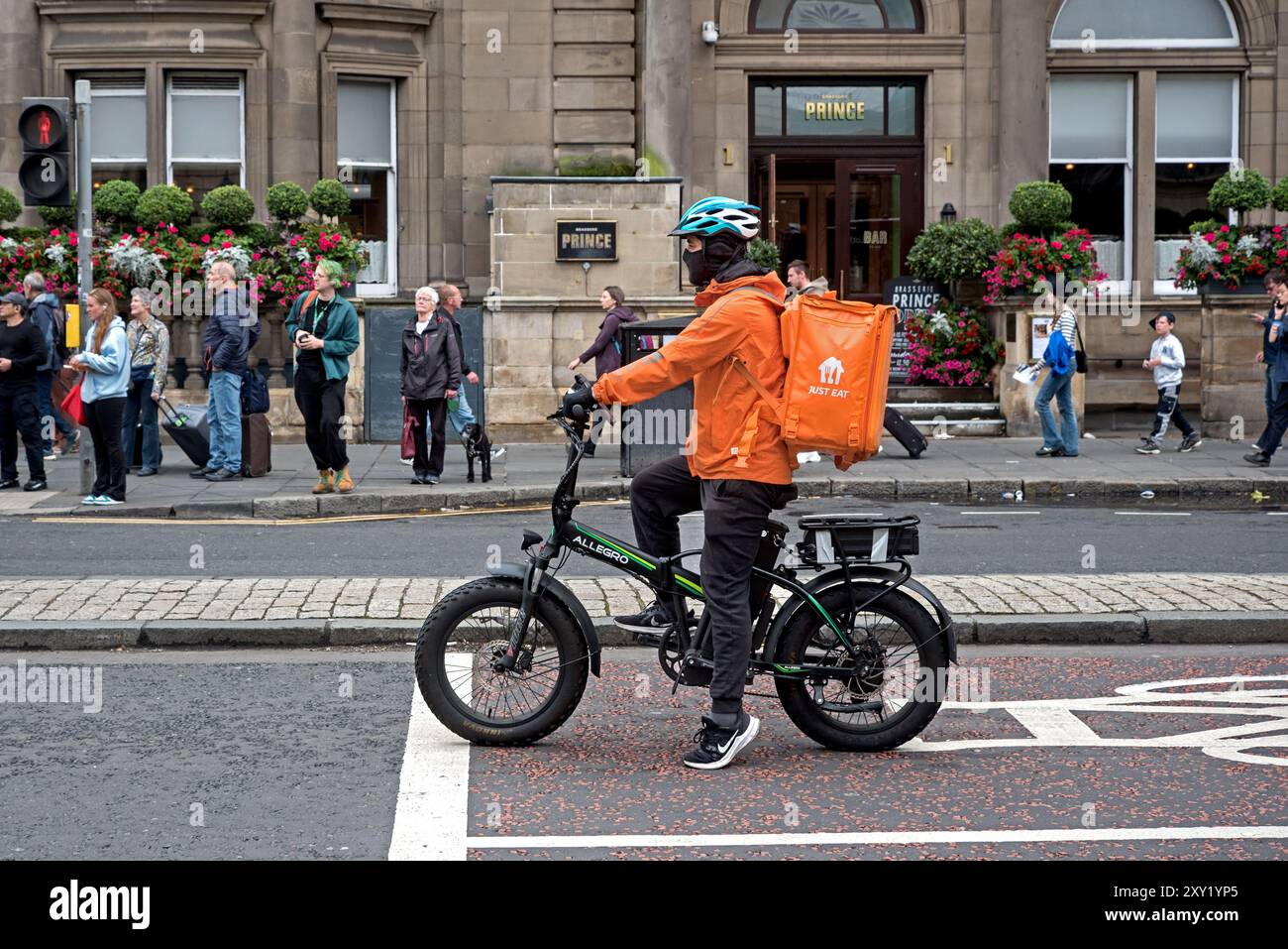 Essen Sie einfach Essen Lieferradfahrer warten an der Ampel auf der Prince Street, Edinburgh, Schottland, Großbritannien. Stockfoto