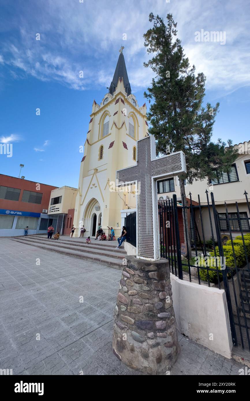 Ein Metallkreuz vor der St. Peter-Apostel-Kirche in San Pedro de Jujuy, Argentinien, mit Menschen auch davor. Stockfoto