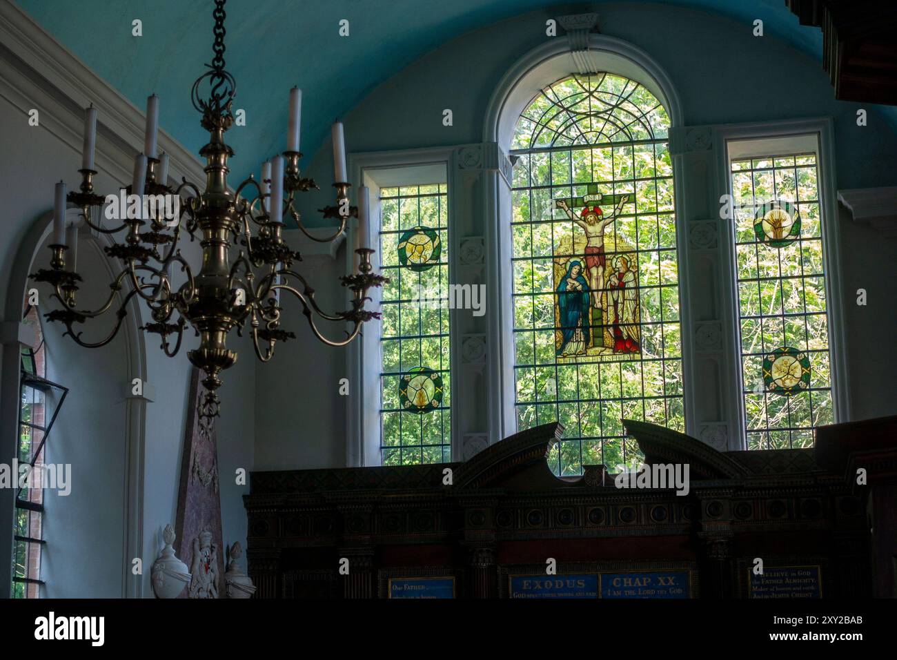 Elegante Buntglasfenster zeigen lebendige biblische Szenen und werfen farbenprächtiges Licht in die stille Kirche St. Marys in Avington, Hampshire, Großbritannien Stockfoto