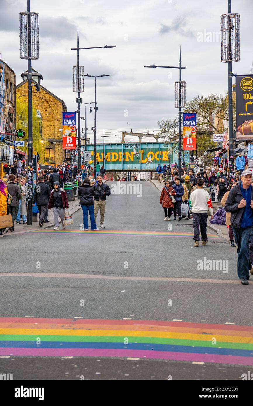 Camden High Street im Stadtviertel Camden Town mit vielen Leuten, die zu Fuß die Geschäfte und die Zebrakreuzungen mit den Regenbogenfarben von Th betrachten Stockfoto