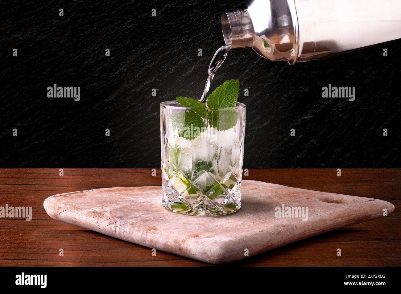 Mojito wird in einem Whiskey-Glas auf einem Schneidebrett gegossen Stockfoto