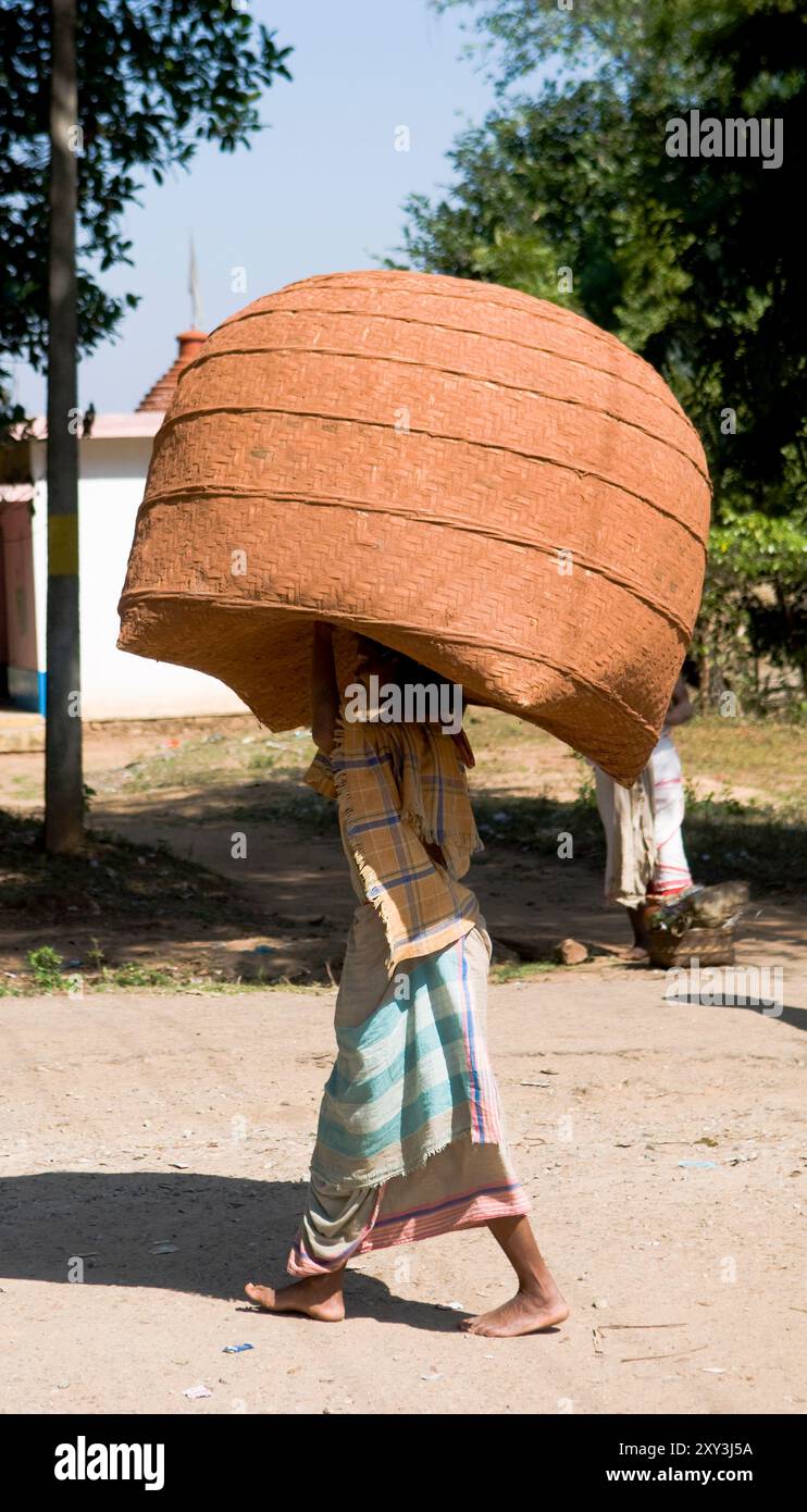 Ein Odia-Mann, der einen riesigen Korb auf dem Kopf trägt. Foto auf einem ländlichen Wochenmarkt im Süden von Odisha, Indien. Stockfoto