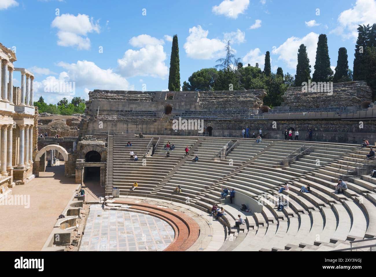 Ein altes Amphitheater mit Steinsitzen unter blauem Himmel mit Wolken und Bäumen im Hintergrund, Teatro Romano de Merida, römisches Theater von Merida, M. Stockfoto