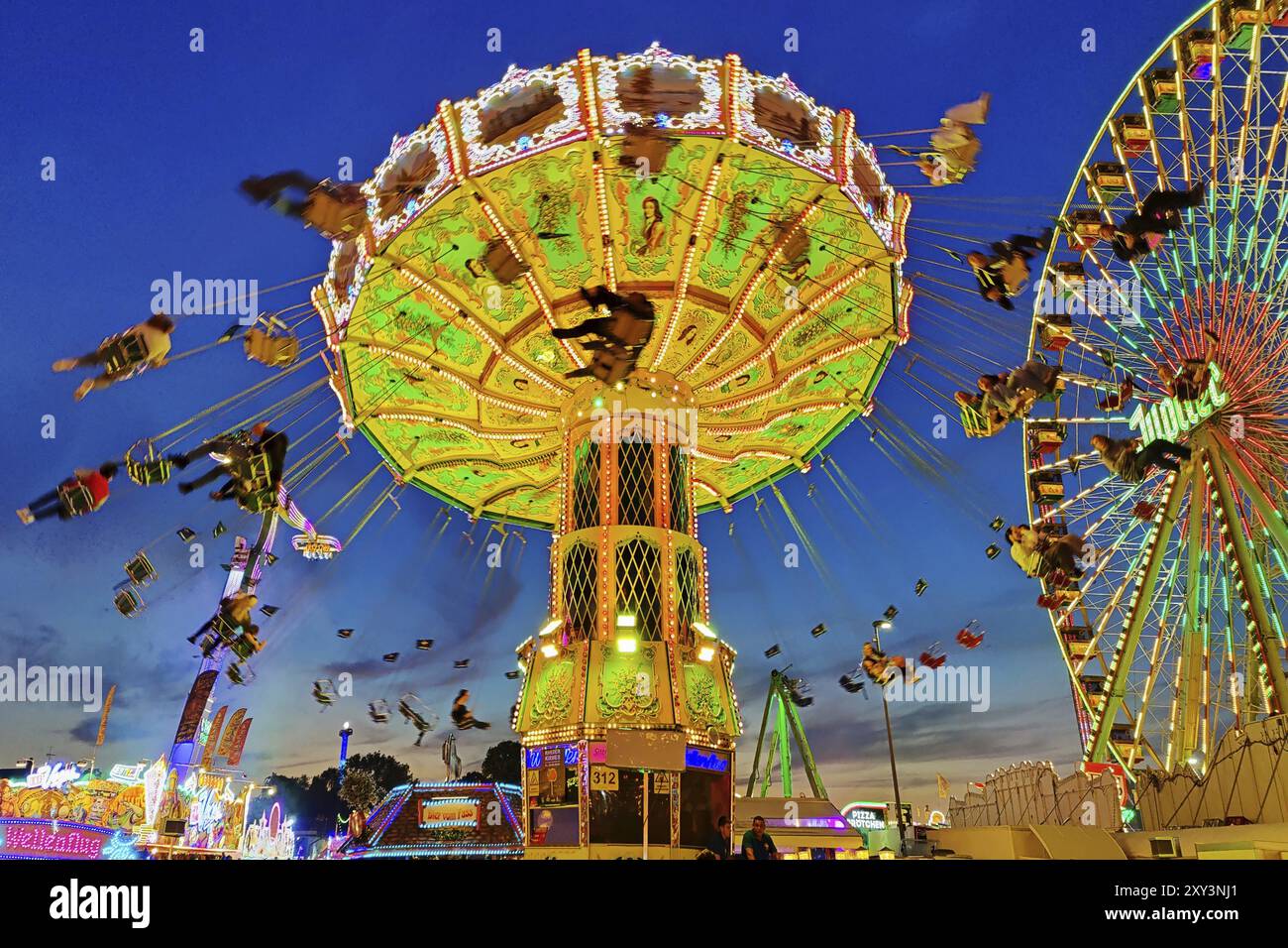 Das bunt beleuchtete Wellenflug Kettenkarussell und das Riesenrad am Abend, Cranger Kirmes, Herne, Ruhrgebiet, Nordrhein-Westfalen, G Stockfoto