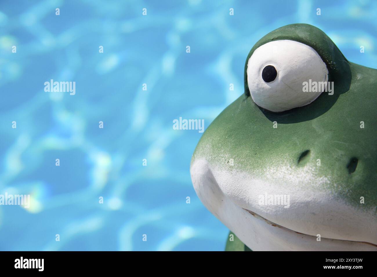 Ein Keramikfrosch vor dem Wasser eines Schwimmbades Stockfoto