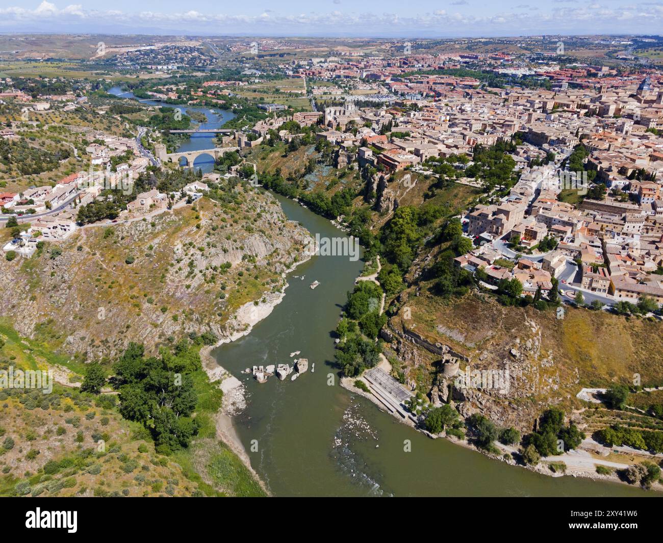 Panoramablick auf eine Stadt mit Häusern auf Hügeln, die von einem Fluss überquert werden, mit einer Brücke im Hintergrund, aus der Vogelperspektive, Toledo, Tejo, Castilla-La Manch Stockfoto