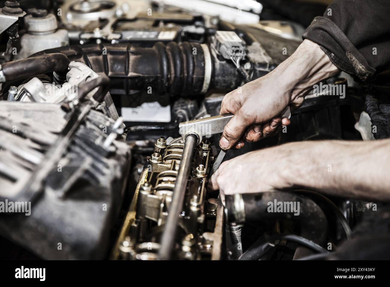 Kfz-Servicemitarbeiter oder Werkstattmechaniker halten ein Fahrzeug-Motorwartungswerkzeug zur Reparatur des Auto-Motors Stockfoto