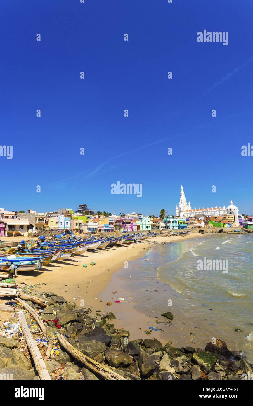 Kanyakumari, Indien, 22. Februar 2015: Die Kirche der Our Lady of Ransom Shrine hinter bunten Häusern an einem Sandstrand, der von Fischerbooten in Tamil Nadu besetzt ist Stockfoto