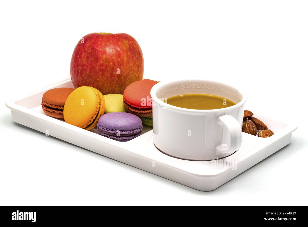Bunte Macarons, Apfel, Mandeln und eine Tasse Kaffee auf einem weißen Tablett zum Frühstück Stockfoto