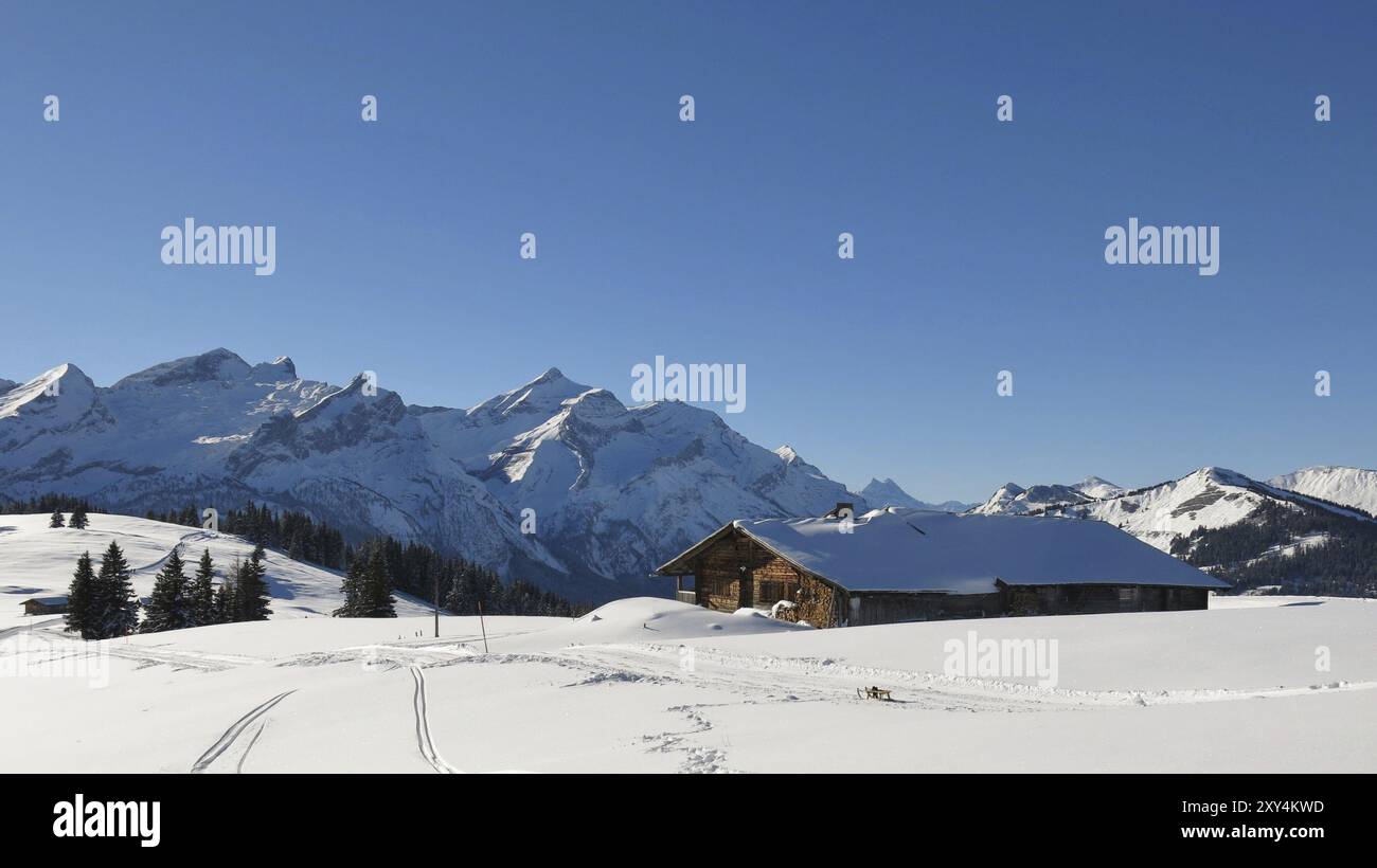 Alte Holzhütte und schneebedeckte Bergkette. Berge Schlauchhorn und Oldenhorn Stockfoto