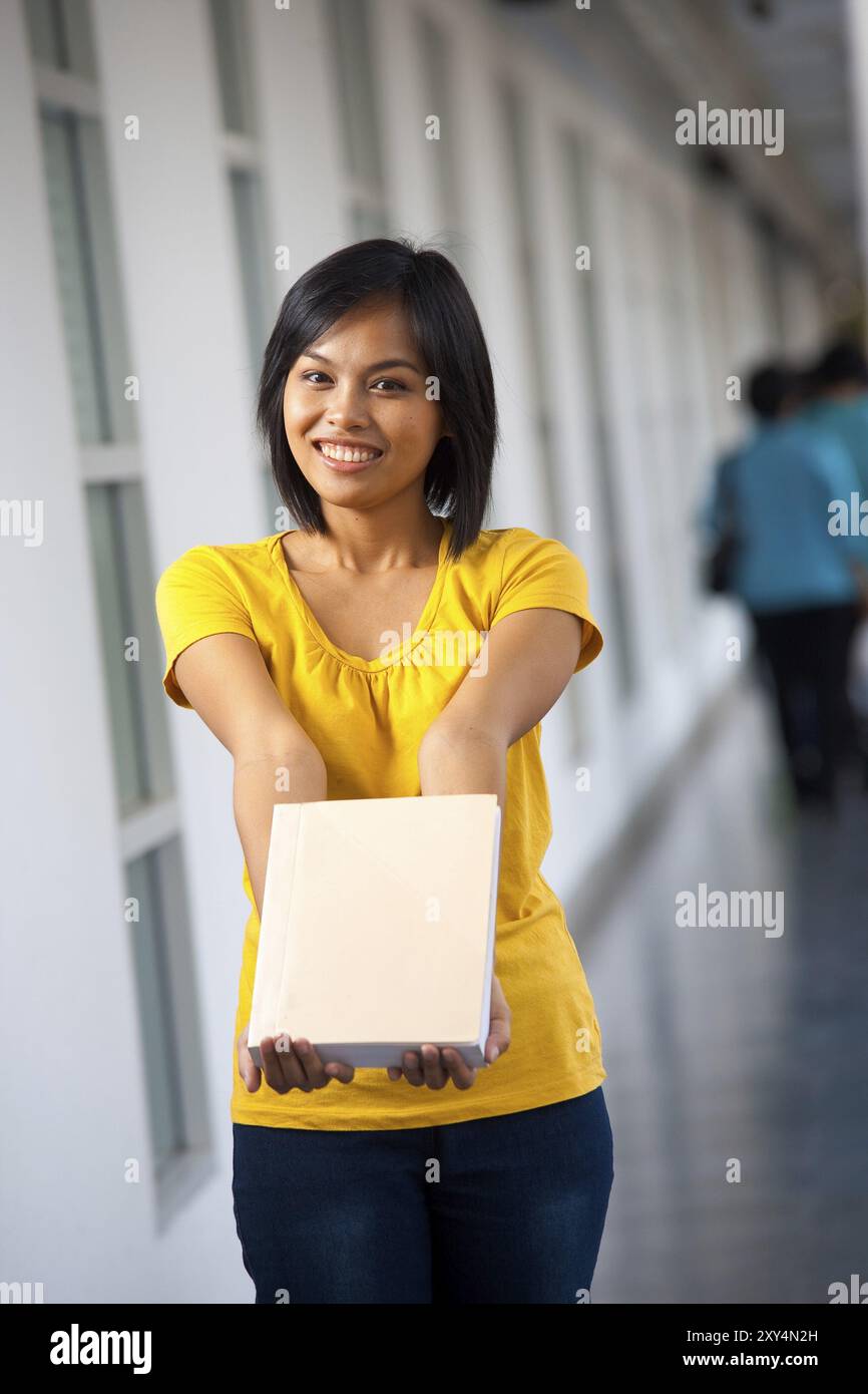 Ein schöner Student zeigt ein leeres Buch, in das Text eingefügt werden kann. 20er Jahre weibliches asiatisches Thai-Modell chinesischer Abstammung Stockfoto