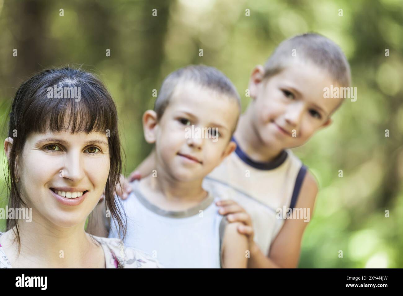 Lächelnde Mutter und kleine Söhne, die im Familienglück draußen laufen Stockfoto