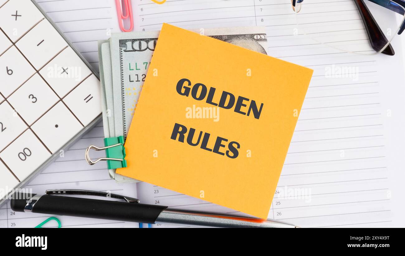 Konzeptionelles goldenes Regelsymbol. Kopierbereich. GOLDENE REGELN auf einem gelben Aufkleber auf amerikanischen Banknoten auf dem Hintergrund eines Geschäftsnotizbuchs Stockfoto