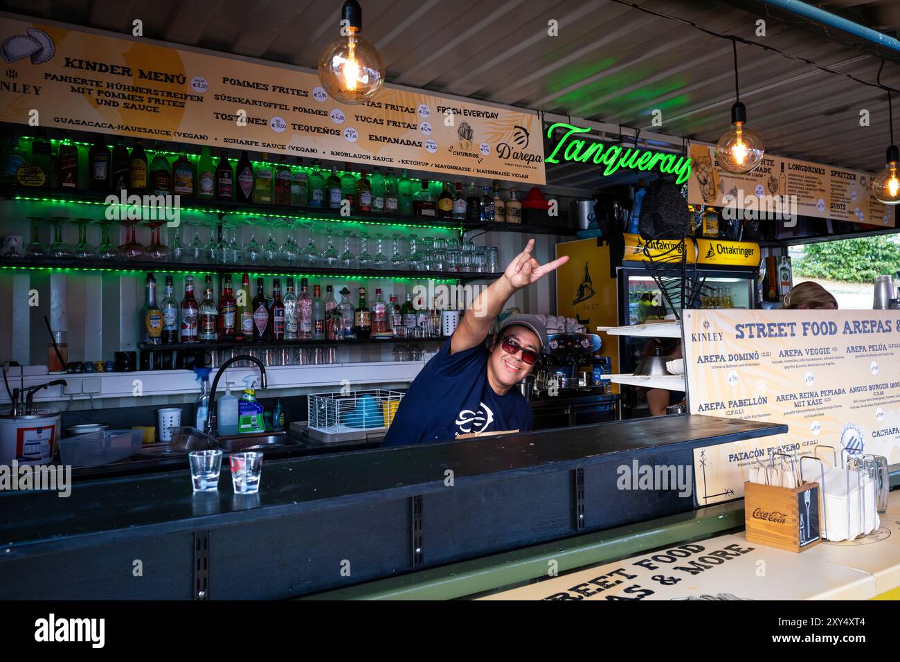 Der Barkeeper der Bar D'arepa begrüßt den Fotografen mit dem Schild Hang Loose Hand, Wien, Österreich Stockfoto