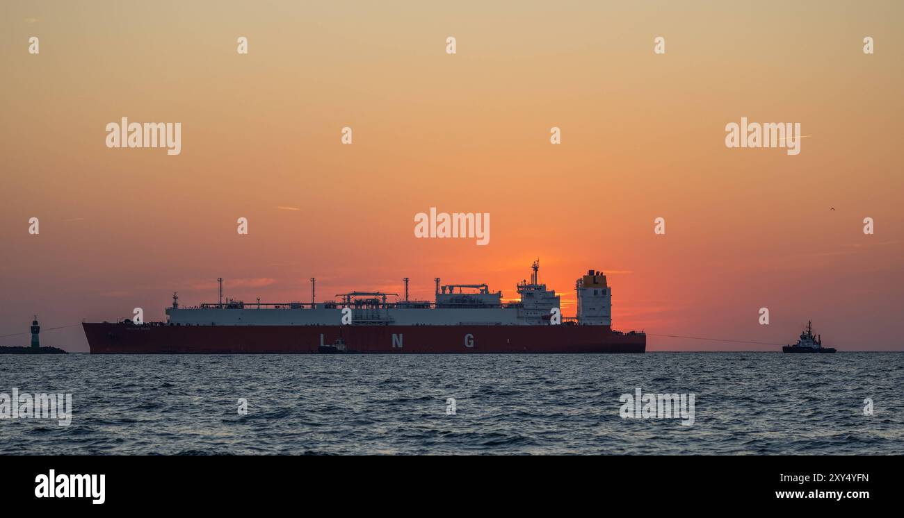 Tanker bringt LNG nach Rügen bei Sonnenaufgang bugsieren Schlepper den LNG-Tanker HELLAS DIANA in den Hafen Mukran auf der Insel Rügen. Das 299 Meter lange Schiff bringt die dritte Flüssigerdgas-Lieferung in diesem Jahr für das einzige deutsche Ostsee-LNG-Terminal. In Mukran wird das LNG umgewandelt, danach durch eine Pipeline von der Insel Rügen bis zum Gasknotenpunkt Lubmin gepumpt und dort in das Gasnetz eingespeist. Mukran Mecklenburg-Vorpommern Deutschland *** Tanker bringt LNG nach Rügen bei Sonnenaufgang schleppt der LNG-Tanker HELLAS DIANA in den Hafen Mukran auf der Insel Rue Stockfoto