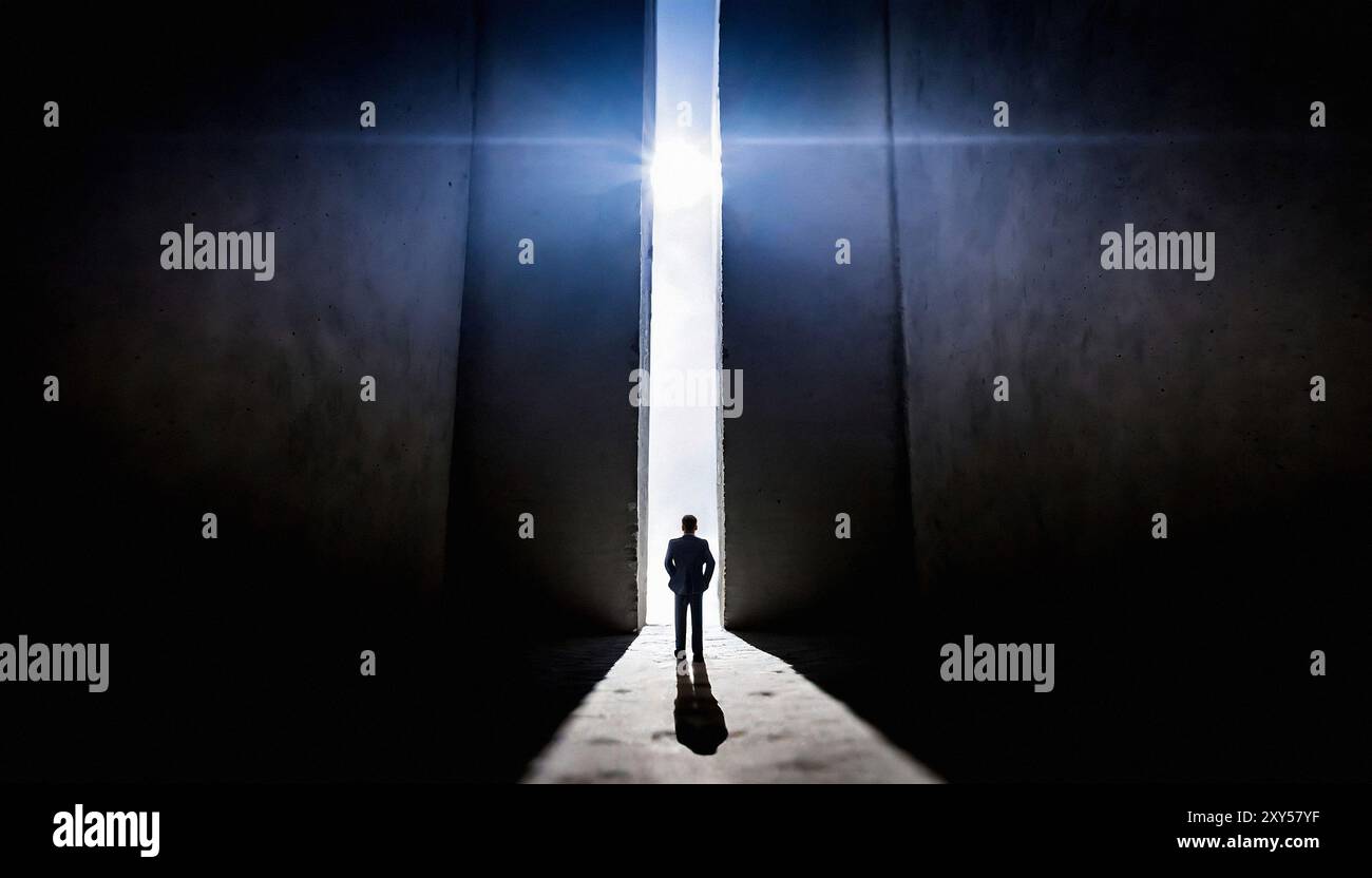 Silhouette eines Mannes, der vor einer Öffnung zwischen zwei riesigen hohen Wänden steht Stockfoto