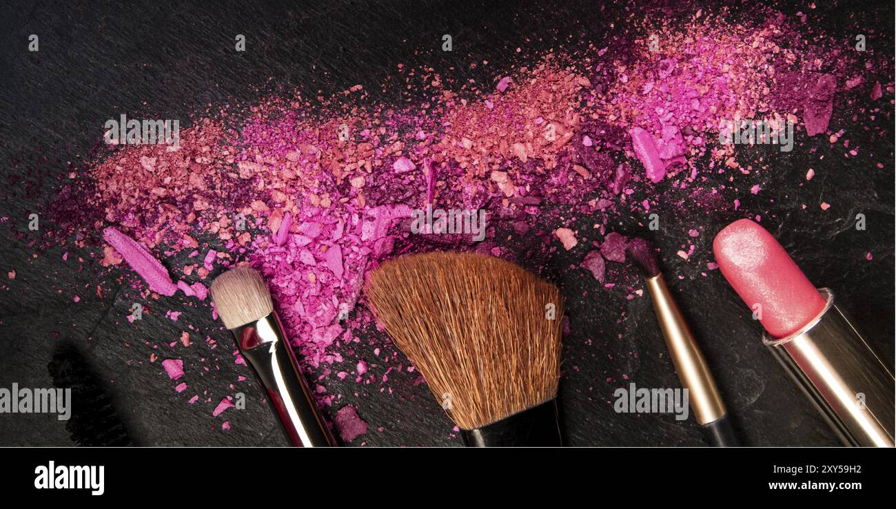 Ein Panorama aus Make-up-Pinseln, Lippenstift und zerquetschter Kosmetik, von oben auf schwarzem Hintergrund mit einem Platz für Logo, ein Schönheitsdesign-templat Stockfoto
