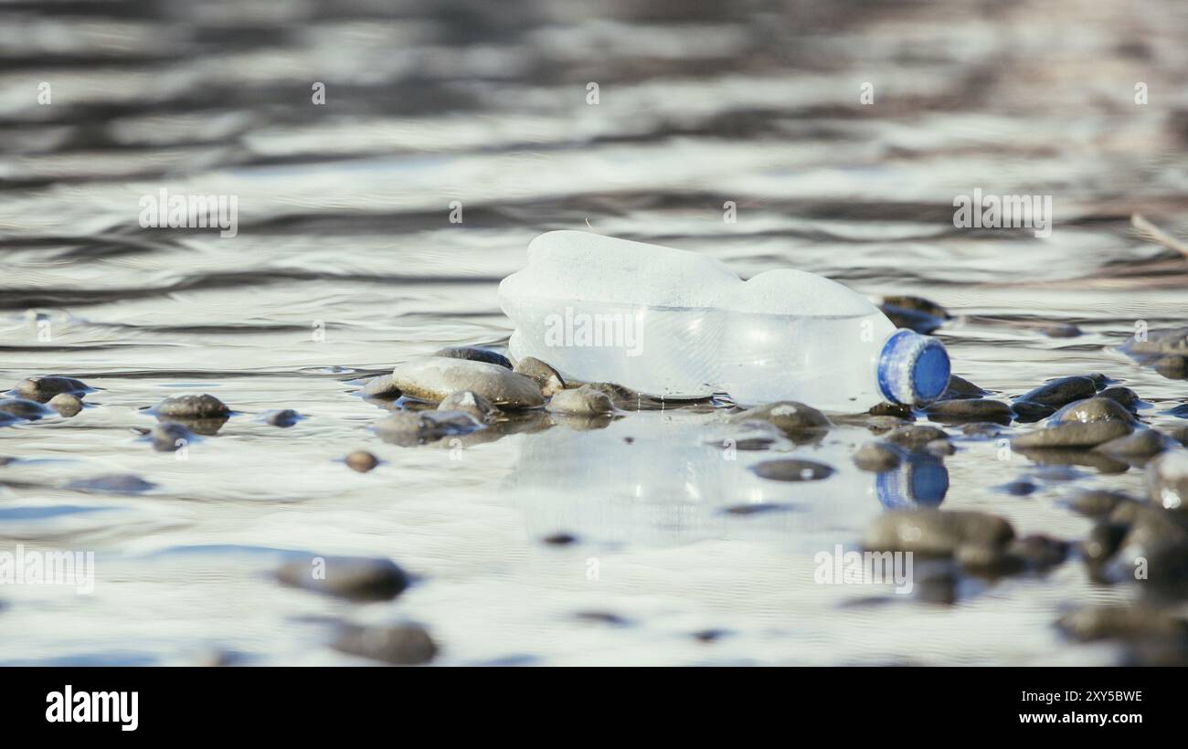 Plastikflasche liegt auf dem steinigen Strand, Umweltverschmutzung Stockfoto