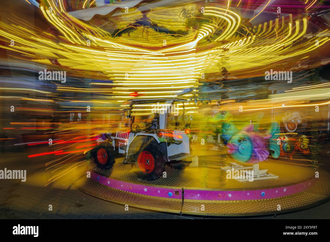 Kinderkarussell in Bewegung auf einem abendlichen Weihnachtsmarkt Stockfoto