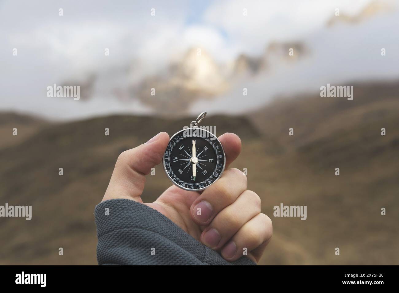 Ein männlicher Wanderer sucht im Herbst eine Richtung mit einem magnetischen Kompass in den Bergen. POV-Aufnahme. Die Hand eines Mannes mit einem Uhrenarmband Stockfoto
