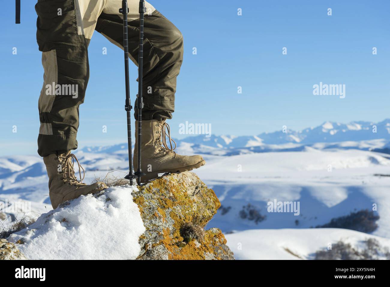 Nahaufnahme des Fußes eines Touristen in Trekkingschuhen mit Stöcken für Nordic Walking auf einem Felsstein in den kaukasischen Bergen Stockfoto