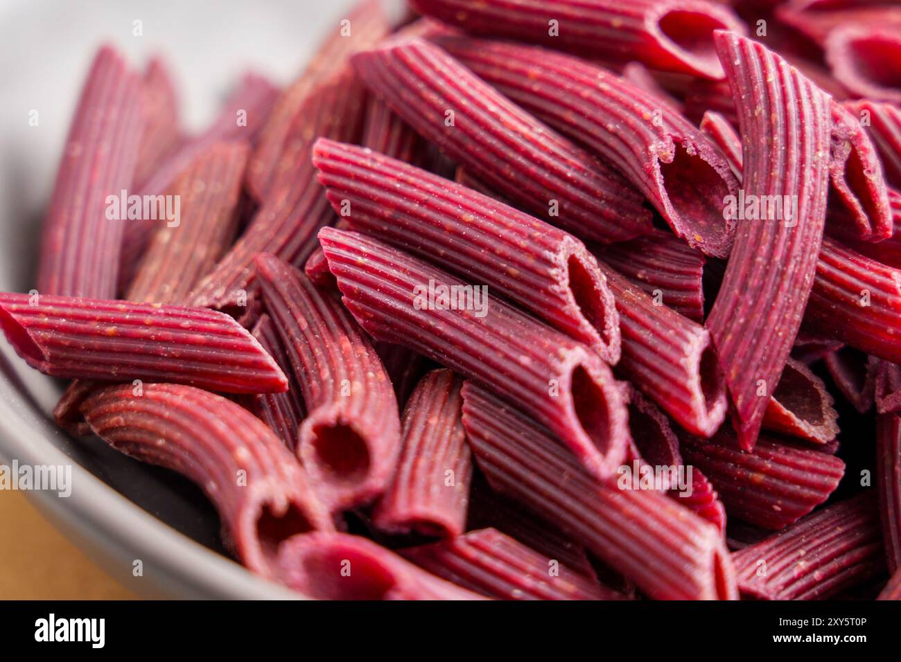 Rote Rüben-Penne-Pasta. Rohe glutenfreie Nudeln. Diät ungekochte Makkaroni. Makroaufnahme. Stockfoto