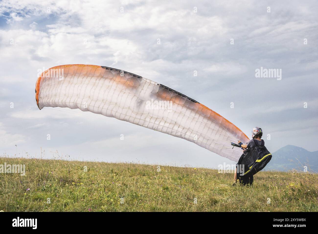 Der Gleitschirmflieger öffnet seinen Fallschirm, bevor er vom Berg im Nordkaukasus abhebt. Füllen Sie den Fallschirmflügel vor dem Start mit Luft Stockfoto