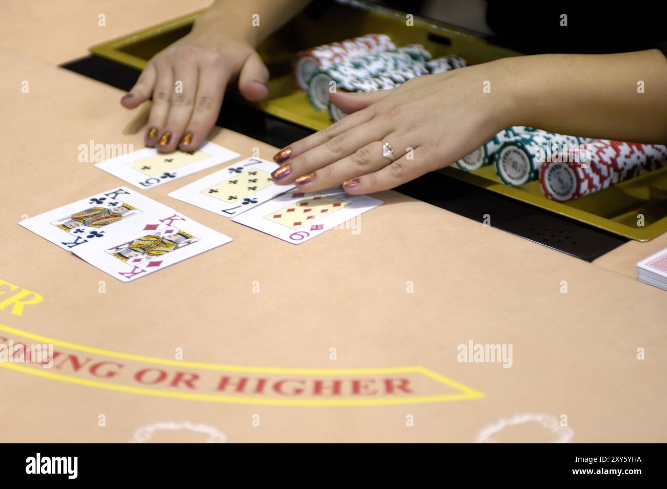 Hände eines weiblichen Croupiers an einem Blackjack-Kartentisch, der die Karten in einem Casino ausgibt Stockfoto