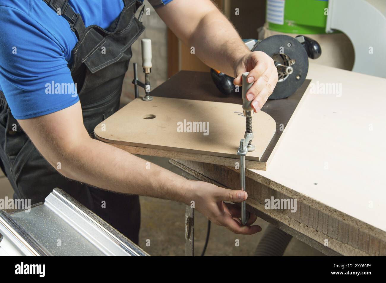 Close Up Master klemmt das Werkstück mit einer dvp-Klemme an der Werkbank und auf dem Hintergrund liegt der Handfräser von Carpentry Stockfoto