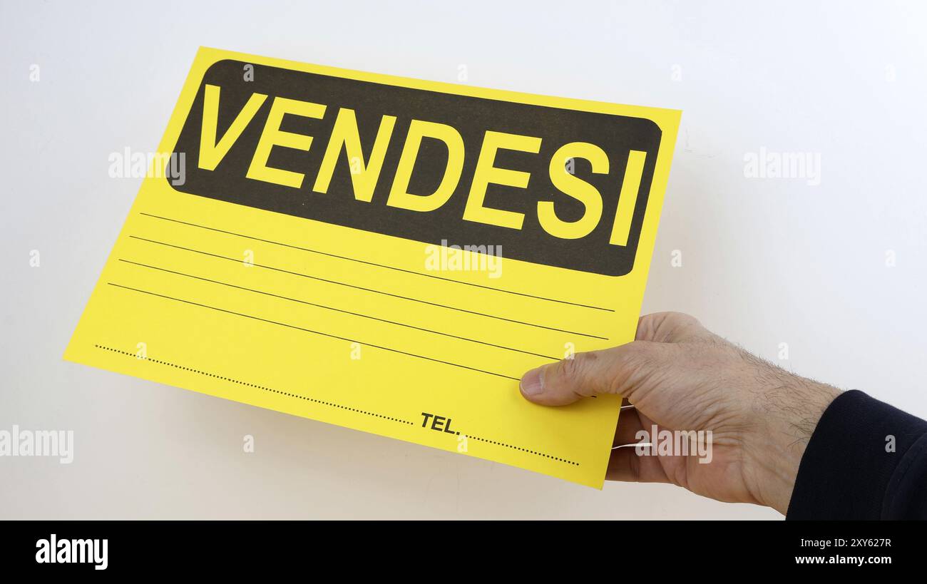 Zum Verkauf steht ein Schild in italienischer Sprache, mit der Hand des Erwachsenen, die den Schild hält, weißer hintergrundter Kopierraum. Stockfoto Zum Verkauf steht ein Schild in italienischer Sprache, mit der Hand des Erwachsenen, die den Schild hält, weißer hintergrundter Kopierraum. Stockfoto