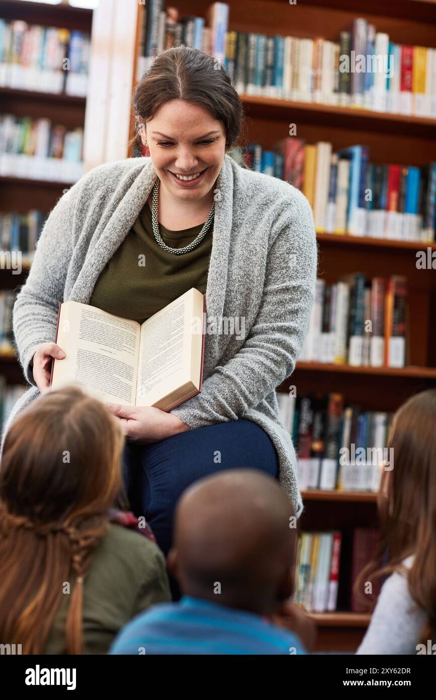 Frau, Lehrerin und Vorlesung für Kinder in Bibliothek, Bildung und Fantasy-Literatur-Fiktion. Weibliche Person, Bibliothekarin Freiwillige und Geschichtenerzählbuch Stockfoto