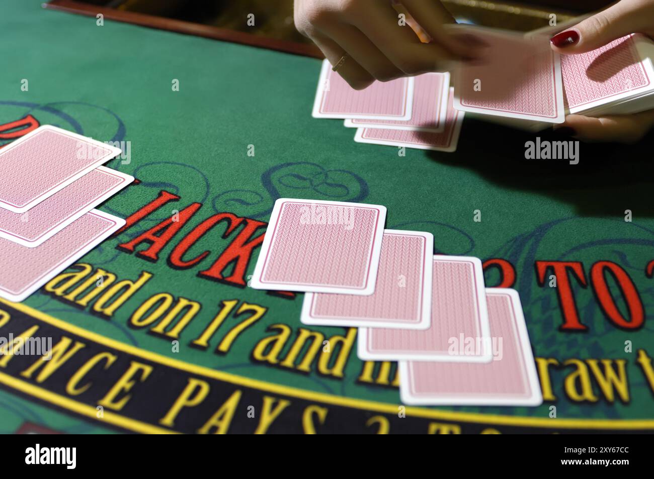 Hände eines Croupier-Händlers an einem Blackjack-Kartentisch, der die Karten in einem Casino ausgibt Stockfoto