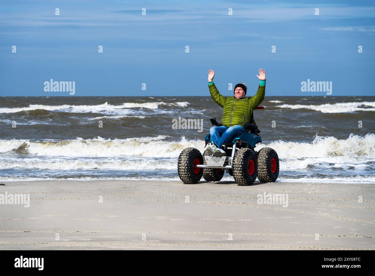 Mann im Strandrollstuhl, hebt Arme in Freude, Sankt-Peter-Ording, Schleswig-Hostein, Deutschland, Europa Stockfoto