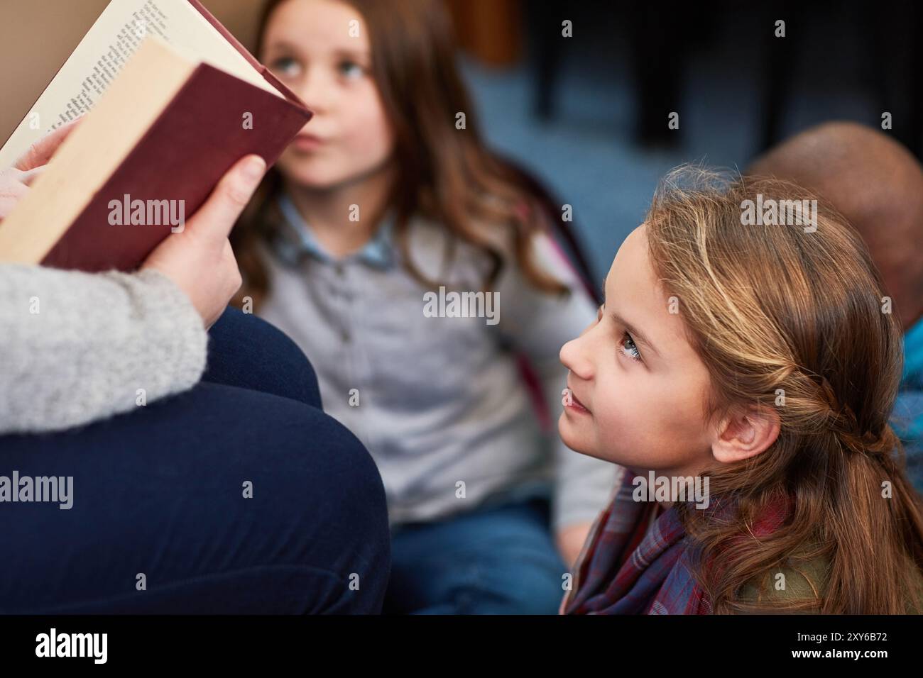 Frau, Lehrer und Kinder hören Geschichten in der Bibliothek, Bildung und Fantasy-Literatur. Weibliche Person, Bibliothekarin Freiwillige und Lesebuch Stockfoto