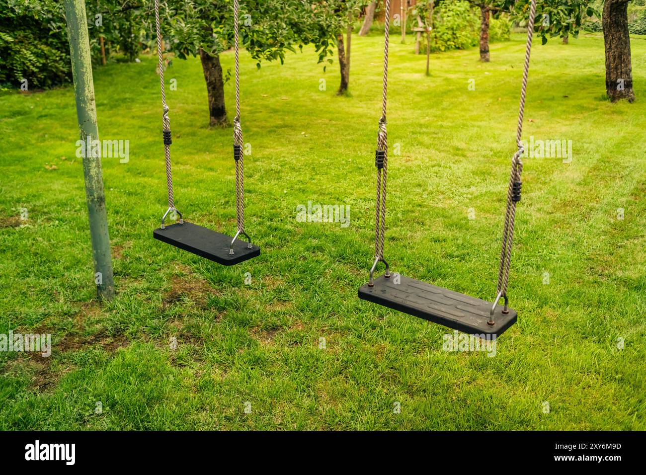 Kinder schaukeln in einem leeren Park oder Garten Stockfoto