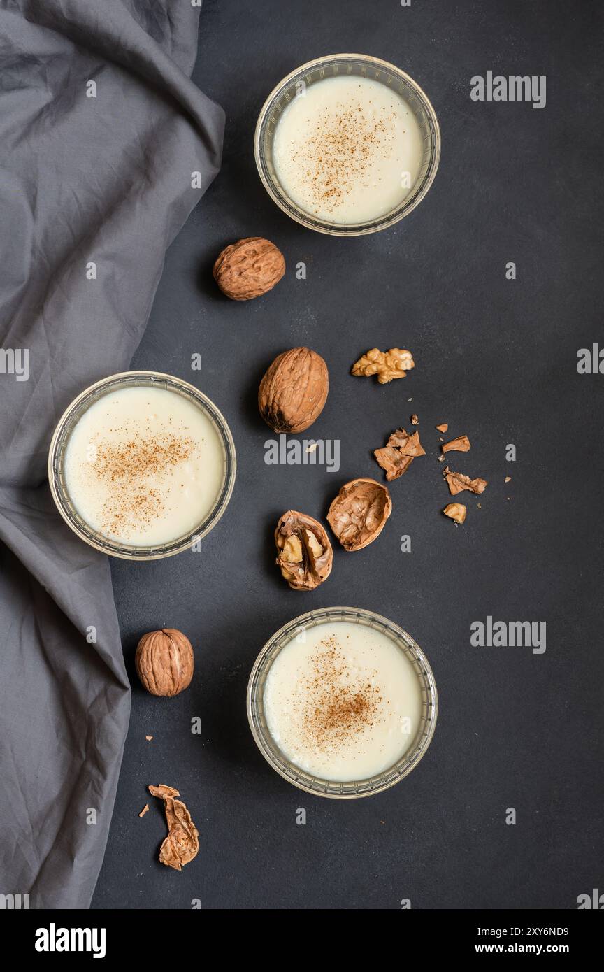 Pudding in Glasschale mit Zimt und Walnuss auf rustikalem Tisch, Milchdessert Stockfoto