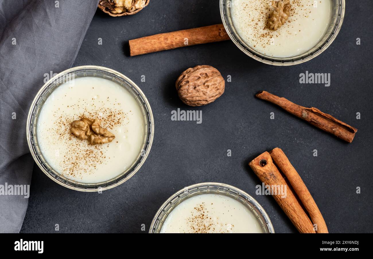Pudding in Glasschale mit Zimt und Walnuss auf rustikalem Tisch, Milchdessert Stockfoto