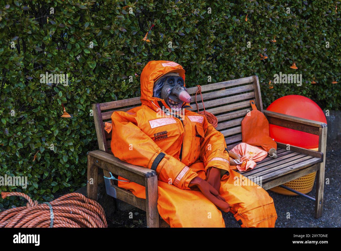 DJUPIVOGUR, ISLAND, 21. JUNI: Dummy einer Hexe mit einem hässlichen und gruseligen Gesicht in einem orangen Overall sitzt am 21. Juni 2013 auf einer Holzbank in Djupivogur, Stockfoto