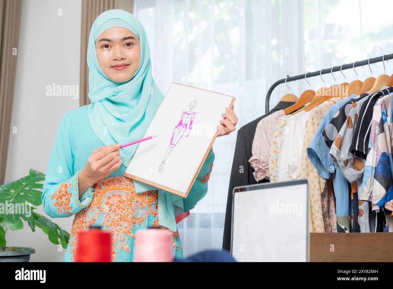 Der Besitzer eines kleinen Schneidergeschäfts stellt Kleidungsstücke vor Stockfoto