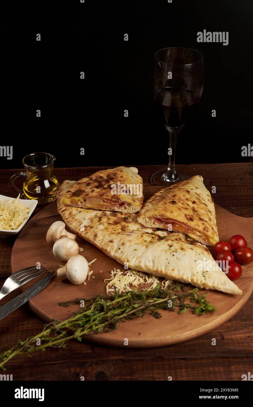 Calzone, traditionelle italienische Zubereitung, begleitet von Gewürzen und Rotwein Stockfoto