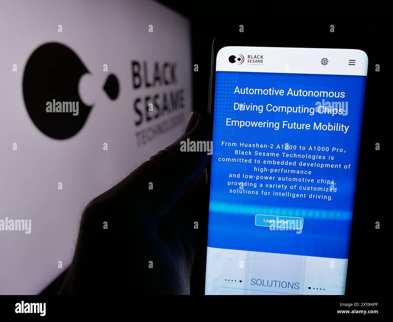 Person, die ein Handy hält, mit der Webseite des Automobilsoftwareunternehmens Black Sesame Technologies vor dem Logo. Konzentrieren Sie sich auf die Mitte des Telefondisplays. Stockfoto