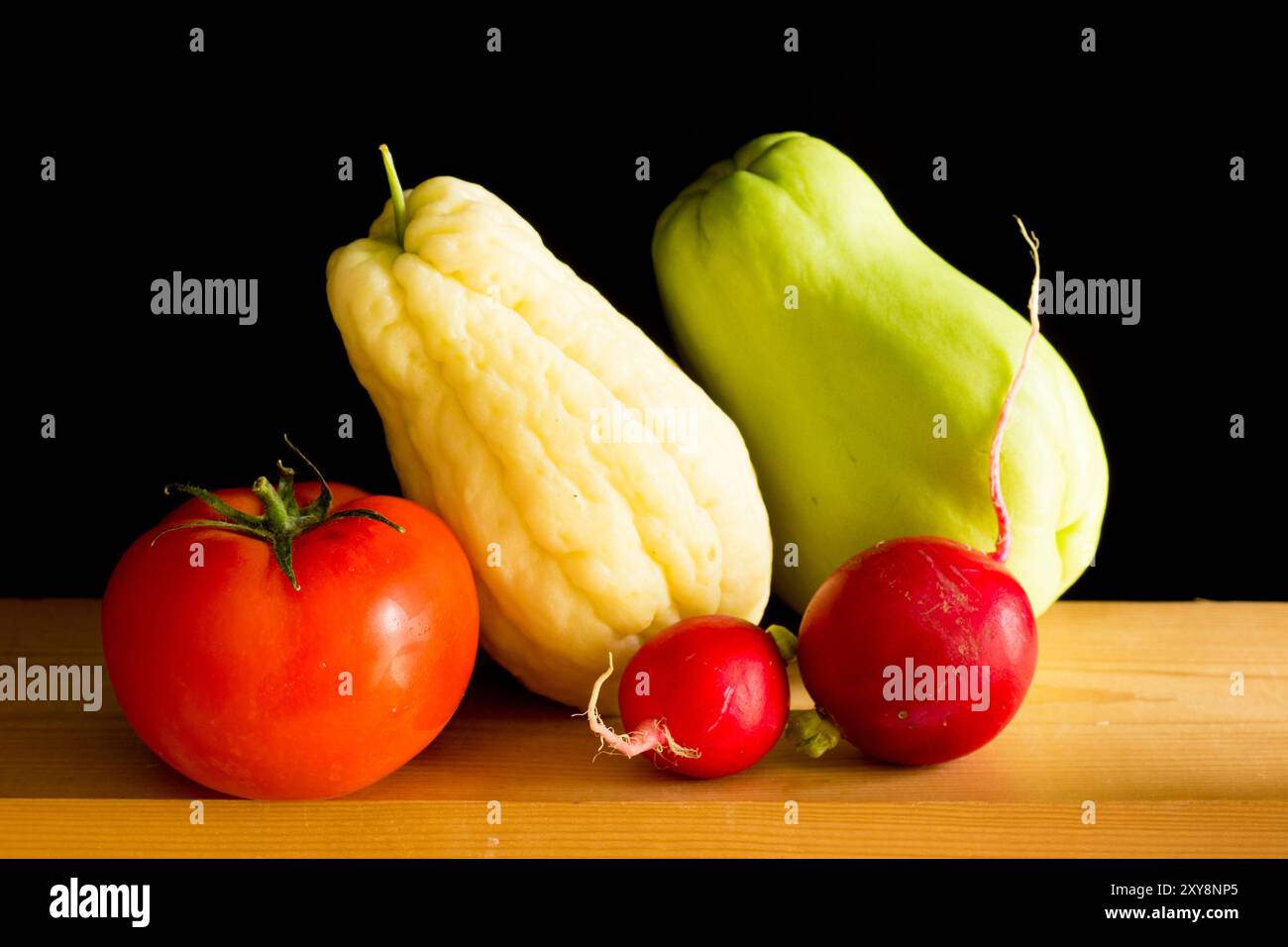 Verschiedene und bunte Gemüse auf einem Holztisch, auf schwarzem Hintergrund. Stockfoto