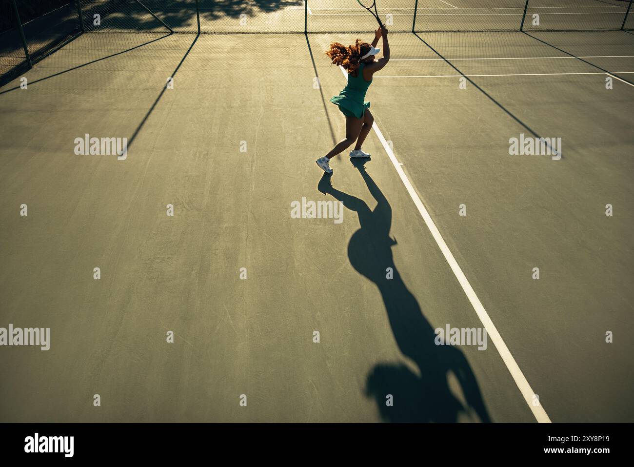 Die Silhouette eines Tennisspielers auf dem Platz während einer Rallye bei Sonnenuntergang unterstreicht die dynamische Bewegung und die schöne Beleuchtung. Stockfoto