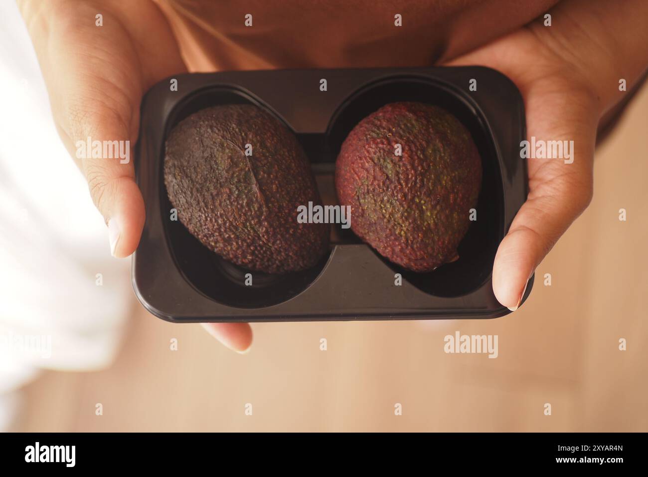 Frisch geerntete Avocados in einem schwarzen Kunststoffbehälter zum Verkauf Stockfoto