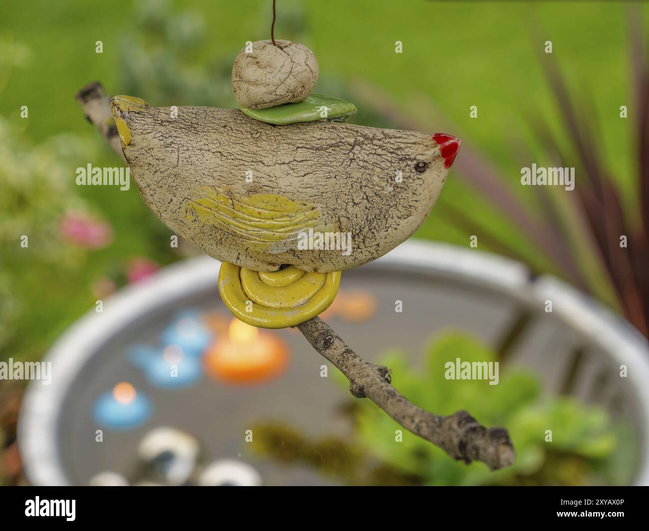 Detail eines dekorativen Tonvogels, der an einem Zweig vor einem Teich mit schwimmenden Kerzen gehängt wurde, borken, münsterland, deutschland Stockfoto