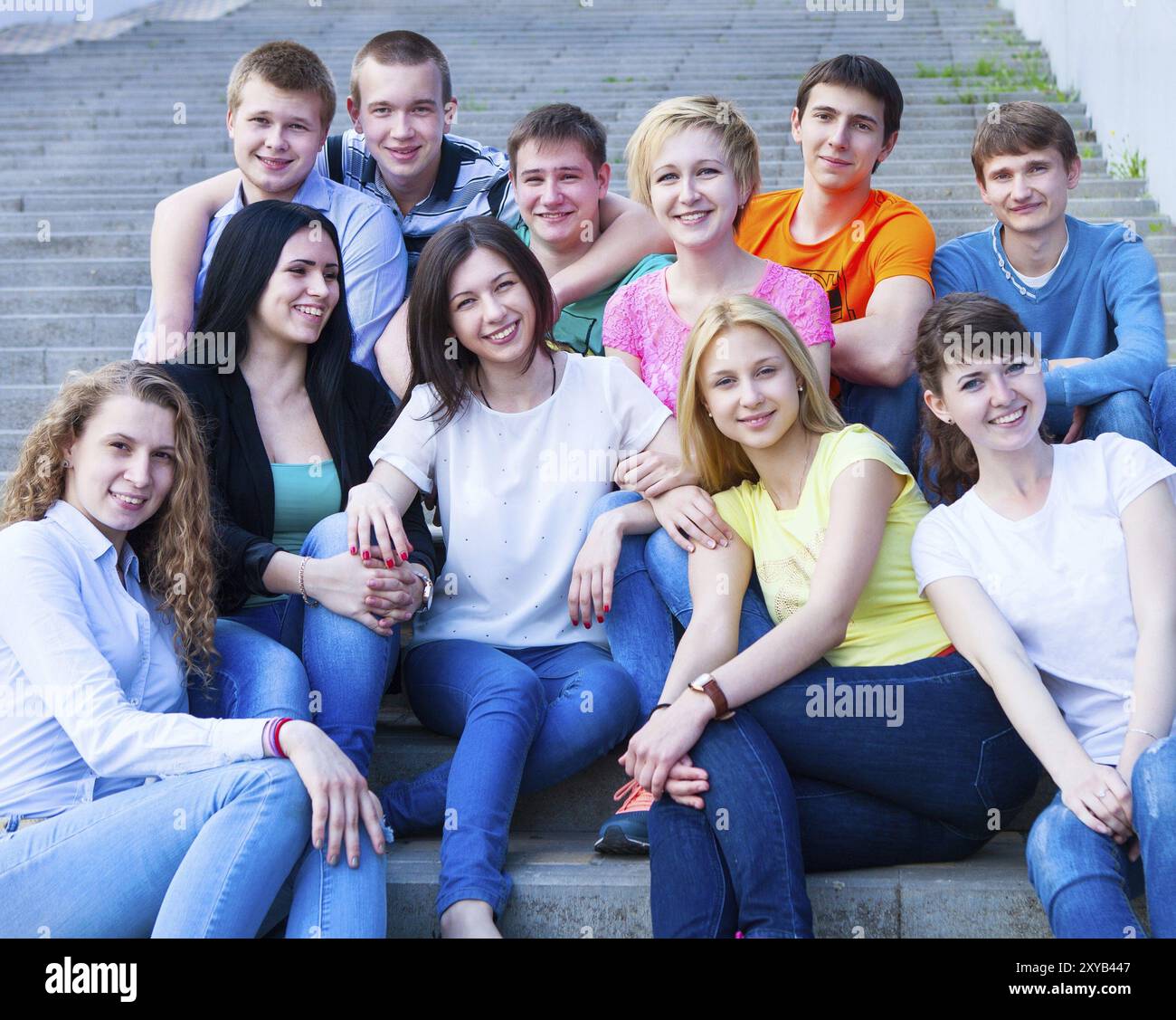 Gruppe von lächelnden Jugendlichen im Freien sitzen. Freundschaft-Konzept Stockfoto