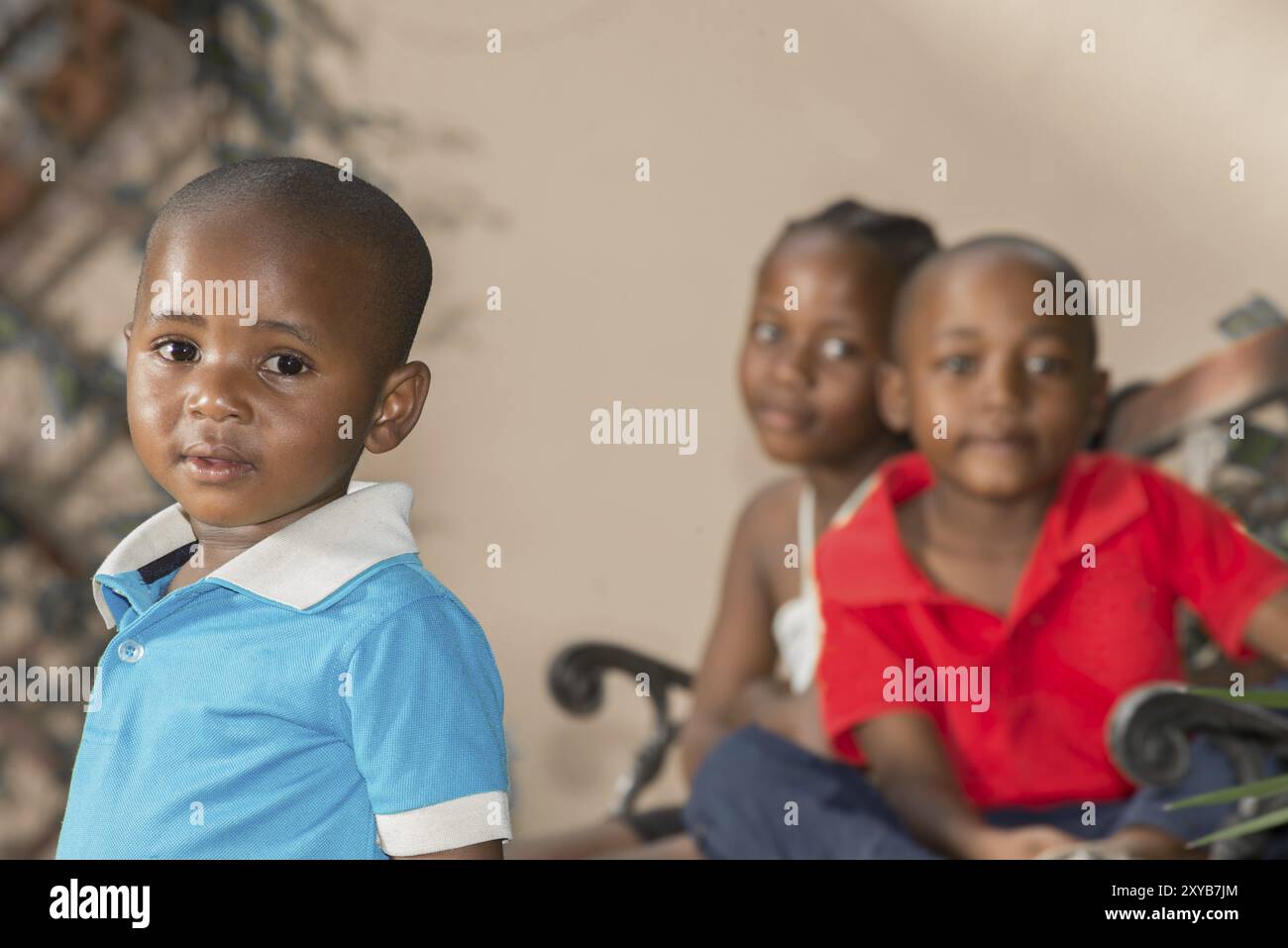 Kleiner Junge mit seinem älteren Bruder und seiner Schwester, die Zwillinge sind, sitzen hinter ihm Stockfoto