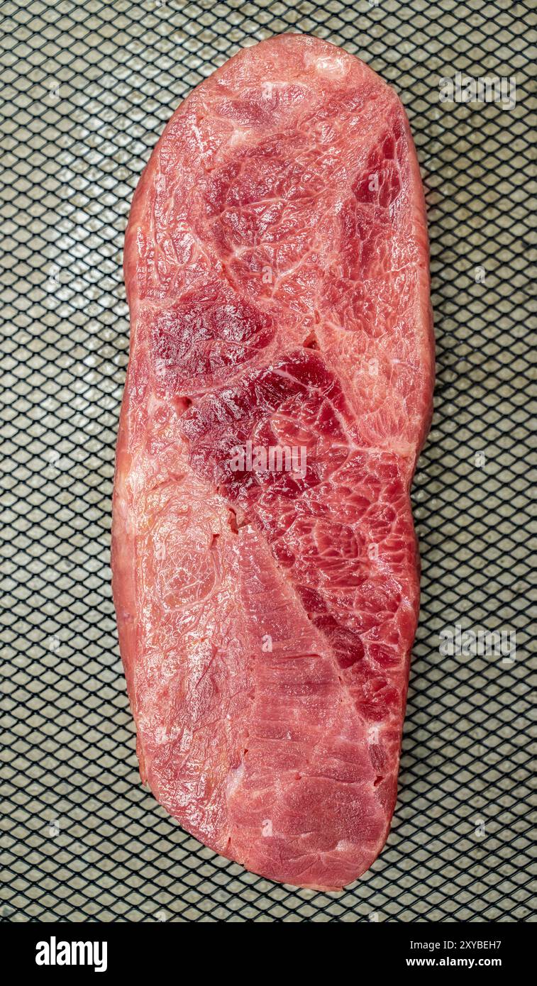 Ein Stück Lendenfleisch wird in Scheiben geschnitten und auf ein Backblech gelegt. Das Fleisch ist rosa und hat eine Menge Textur Stockfoto